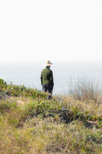 man wearing hat on cliff edge looking at horizon contemplation Contemporary Fine Art White Gray Beach Seasons Landscape real people thinking Cliff Photography