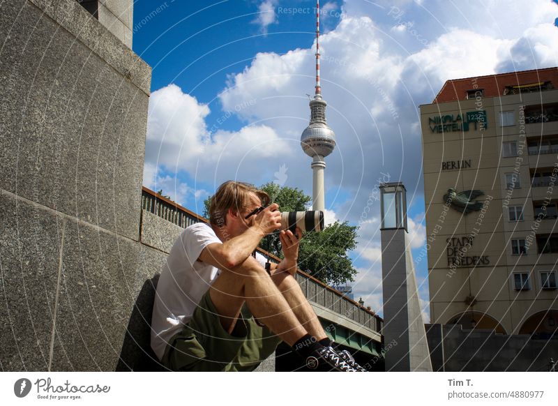 a man takes a photo sitting on the spree river Man Sit Television tower Take a photo Objective canon Berlin Middle Summer Downtown Berlin Berlin TV Tower