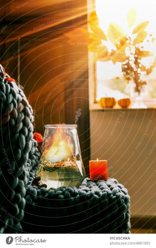 Cozy autumn home interior cozy vase candles grey wool blanket chair window background sunset sunrays still life glass seasonal decoration front view decorative