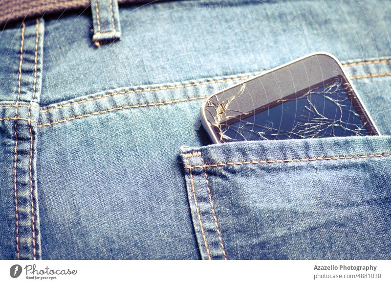 Broken cell phone in a back pocket. Jeans background with a broken smartphone. jeans mobile gadget lcd screen smashed cracked shattered defective minimalism