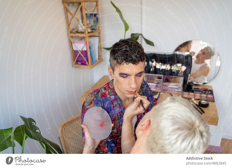 Androgynous Man Getting Makeup Done By Boyfriend At Table Transgender Couple Applying Lipstick Artist Cosmetic Gay Vanity Red Eye Shadow Brush Dressing Together