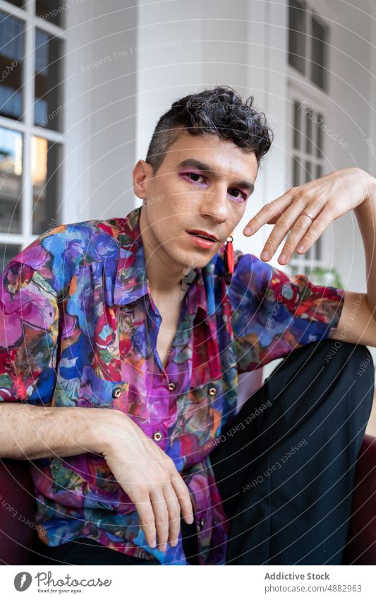 Confident Transgender Man In Casual Sitting On Sideboard Portrait Gay Lifestyle Home Shirt Happy Earring Androgynous Trendy Fashion Looking At Camera Pride