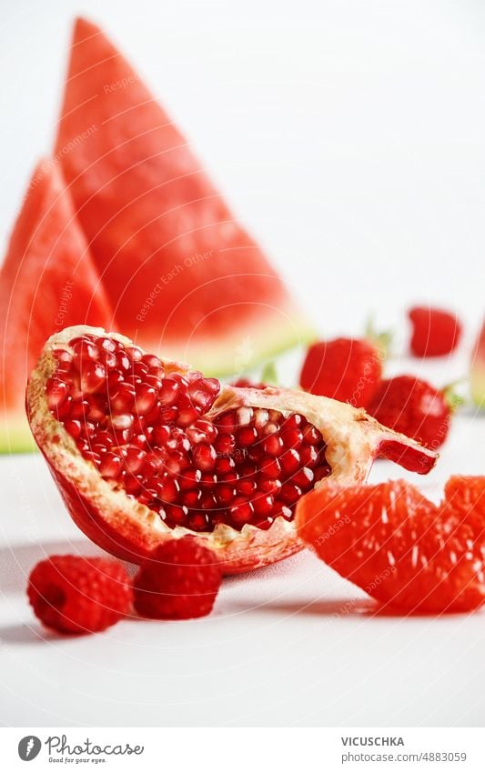Close up of quarter of pomegranate, watermelon, raspberries and grapefruit at white background delicious close up healthy sweet red summer fruits refreshing