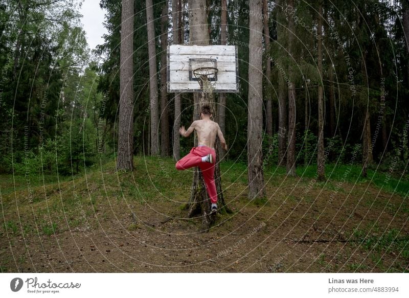Having fun in the woods. Wild boy with pink pants playing some kind of basketball. Sports in a forest on a hot summer day. Basketball rusty muscles sports