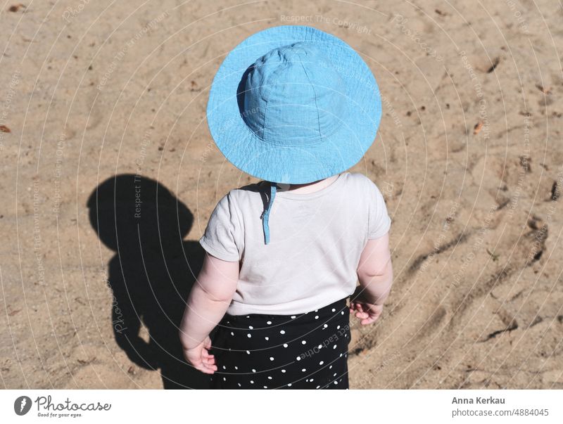 A small child with blue hat marvels at his shadow Child Toddler Girl 1 - 3 years Playground Rear view Shadow Shadow play Sand Blue Hat sun protection
