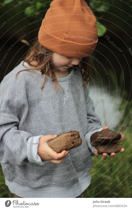 Girl playing with stones by the stream be out play outdoors Sweater oversize Cap Green Grass Brook Nature Infancy Playing Happiness Summer Kindergarten