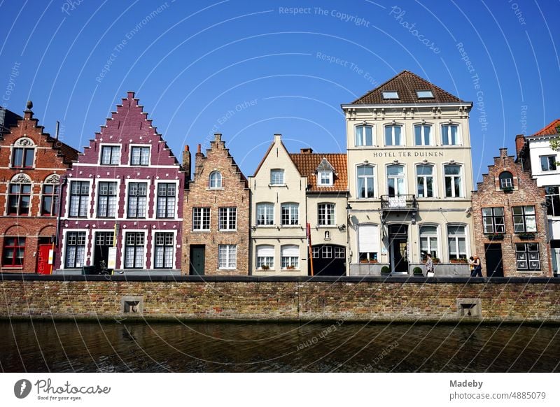 Magnificent colorful restored facades of old houses on the canal against blue sky in the sunshine in the old town of Bruges in West Flanders in Belgium Brugge