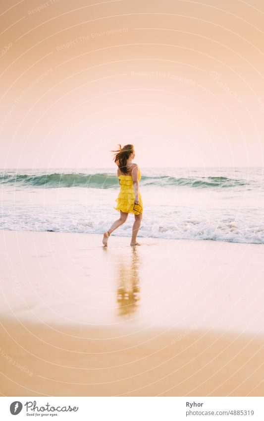 Goa, India. Young Caucasian Woman In Yellow Dress Enjoying Life And Running Towards Sea Waves Arabian Sea Indian Ocean beautiful caucasian distance dress