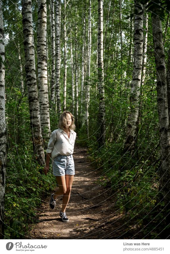 Birches and a blonde girl dressed in shorts and a white shirt. With her gorgeous long legs running in these woods. Enjoying summer and sun. Exploring Lithuanian forests.