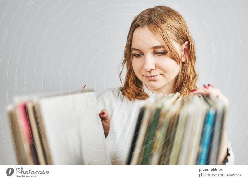 Playing vinyl records. Listening to music from vinyl record player. Retro and vintage music style. Young woman searching analog LP record album in stack of old records