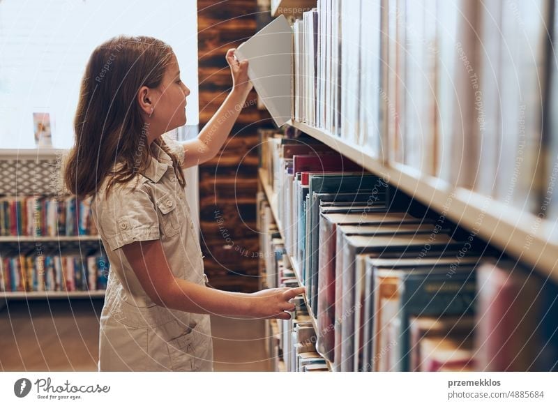 Schoolgirl choosing book in school library. Smart girl selecting books. Learning from books. School education. Benefits of everyday reading. Child curiosity. Back to school