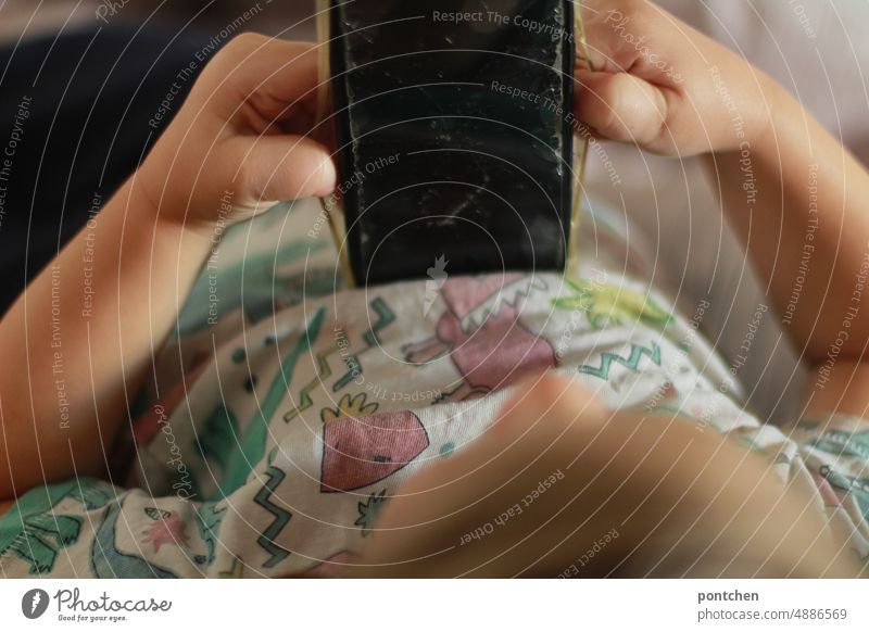 A toddler is lying in bed playing with a cell phone, cell phone. Broken display foil. Child Cellphone mobile phone stop Playing Media usage Infancy digitization