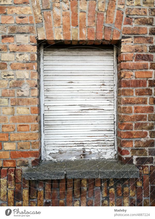 Old window with lowered white shutter in old brickwork of red-brown brick of a residential house in Knokke-Heist on the North Sea near Bruges in West Flanders in Belgium