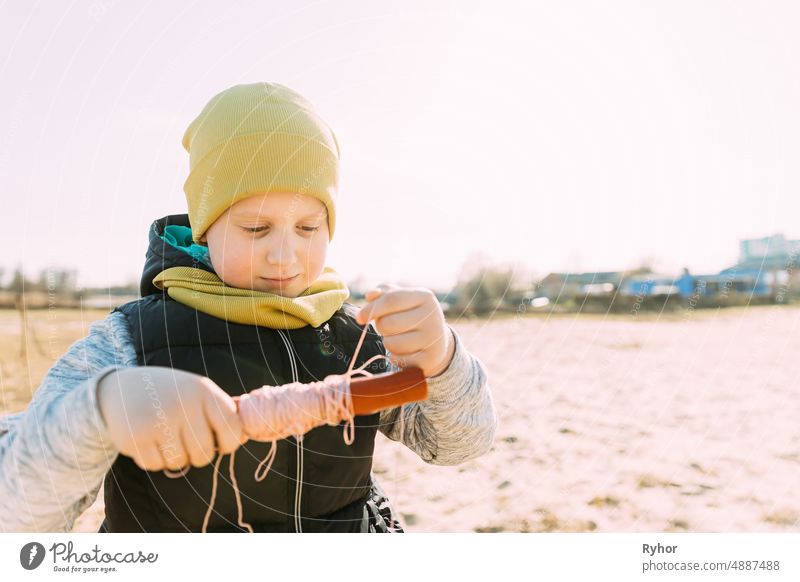 Boy Of 6-7 Years Old Takes Up A Twine From A Kite. Pleasant Activity In Fresh Air On A Sunny Spring Or Autumn Day active activity autumn beautiful boy caucasian