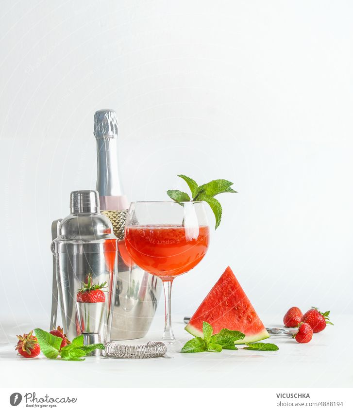 Watermelon cocktail setting with shaker, glass, bottle and fruits at white background. watermelon preparing delicious refreshing summer drink ingredients