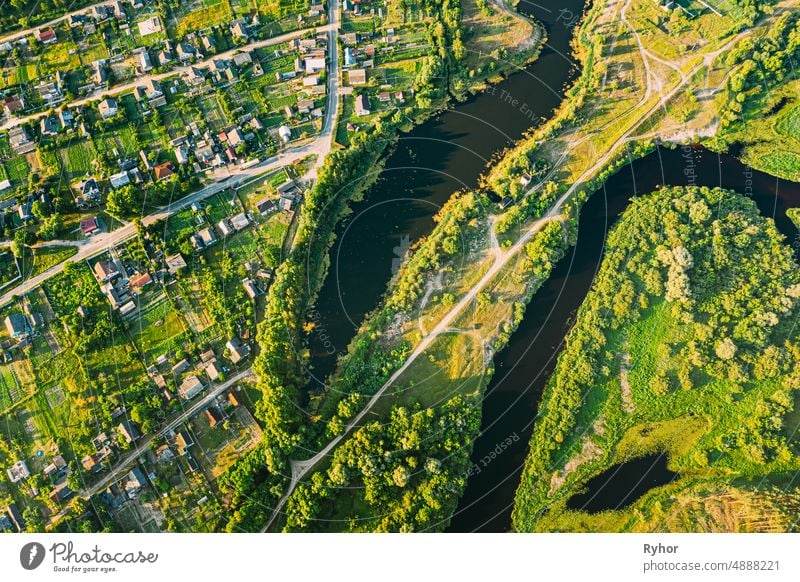 Aerial View Of Calm River And Village In Belarus, Europe. Green Forest Woods Landscape In Sunny Summer Evening. Top View Of Beautiful European Nature From High Attitude. Drone View. Bird's Eye View