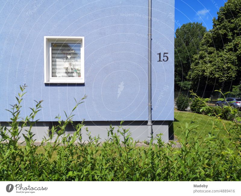 Renovated blue facade with thermal insulation and green front garden in summer sunshine in a housing estate in Oerlinghausen near Bielefeld on the Hermannsweg in the Teutoburg Forest in East Westphalia-Lippe