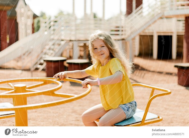A charming little girl is walking in the park, swinging on a swing. Happy childhood, playtime carousel walks happy fun cute kid playground outdoor recreation