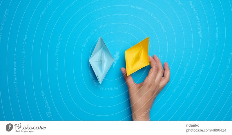 A woman's hand holds a yellow paper boat support ukraine blue ukrainian peace victory independence crisis conflict politic patriotic origami concept palm