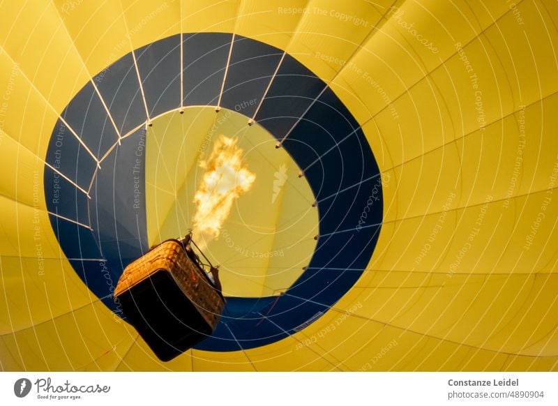 Yellow hot air balloon with basket and big flame seen from below. Nature Aircraft Transport Outdoors Tourism Hot Sky Ballooning travel flight Illuminated early