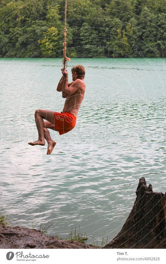 a man swings on a rope to jump into the lake liepnitzsee Brandenburg Man Water Lake Calm Nature Exterior shot Lakeside Colour photo Landscape Tree Day Idyll