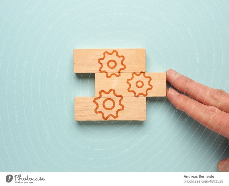 One hand puts the wooden blocks with the gear icon together cogwheel purpose performance people work recycle financial corporate connection businessman