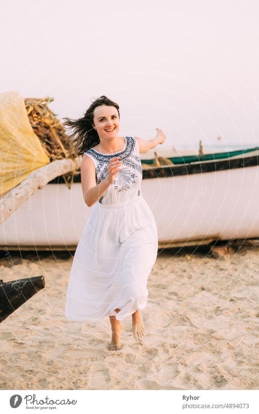 Goa, India. Young Caucasian Woman In White Dress Running On Beach Sand, Enjoying Life And Smiling active beach beautiful caucasian dress enjoy life happy india