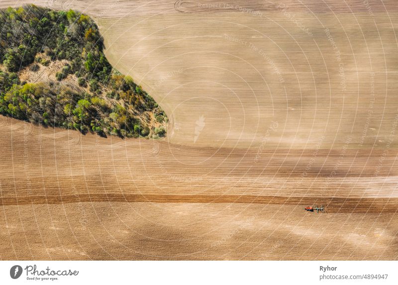 Tractor Plowing Field In Spring. Beginning Of Agricultural Season. Cultivator Pulled By A Tractor In Countryside Rural Field. Countryside Field Landscape. Aerial View. Top Flat View