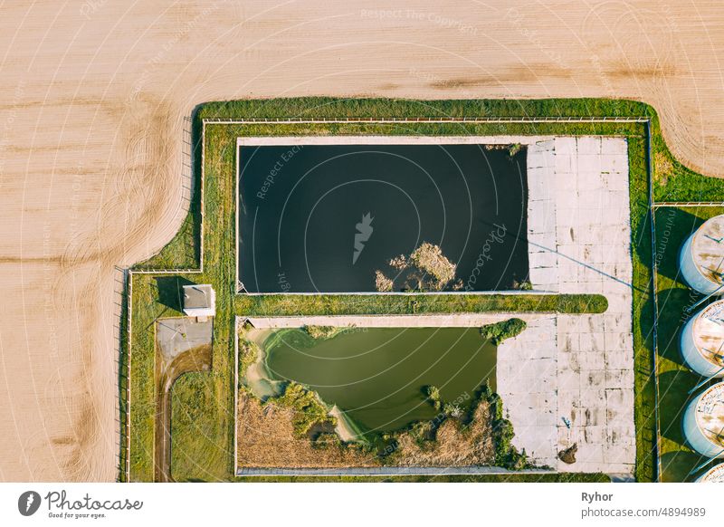 Aerial View Of Retention Basins, Wet Pond, Wet Detention Basin Or Stormwater Management Pond Near Biogas Bio-gas Plant From Pig Farm. Artificial Pond With Vegetation Around Perimeter.