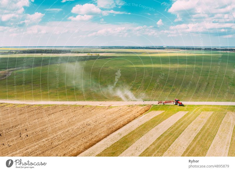 Aerial View. Tractor Plowing Field In Spring Season. Beginning Of Agricultural Spring Season. Cultivator Pulled By A Tractor In Countryside Rural Field Landscape