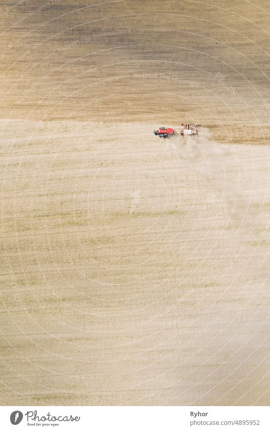 Aerial View. Tractor With Seed Drill Machine Sowing The Seeds For Crops In Spring Season. Beginning Of Agricultural Spring Season. Countryside Field Landscape. Natural Rural Background