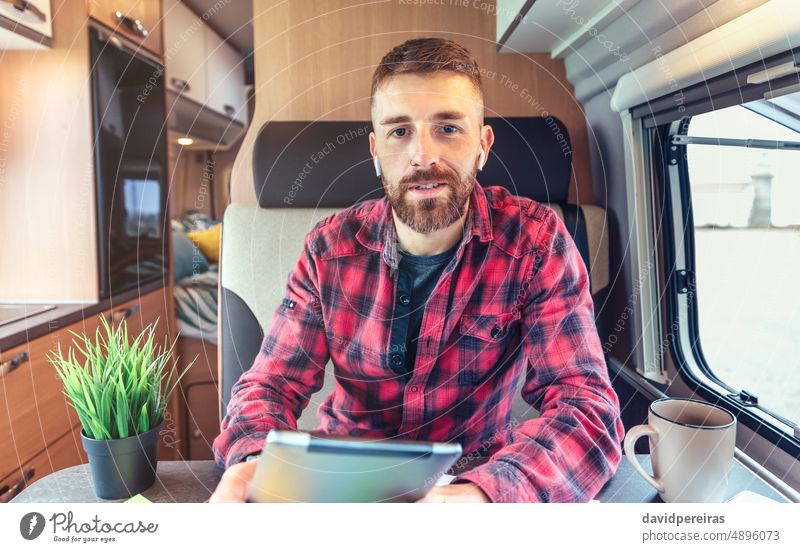 Man talking on videoconference from his campervan man looking camera remote work camper van wireless earphones person business chat interview online call