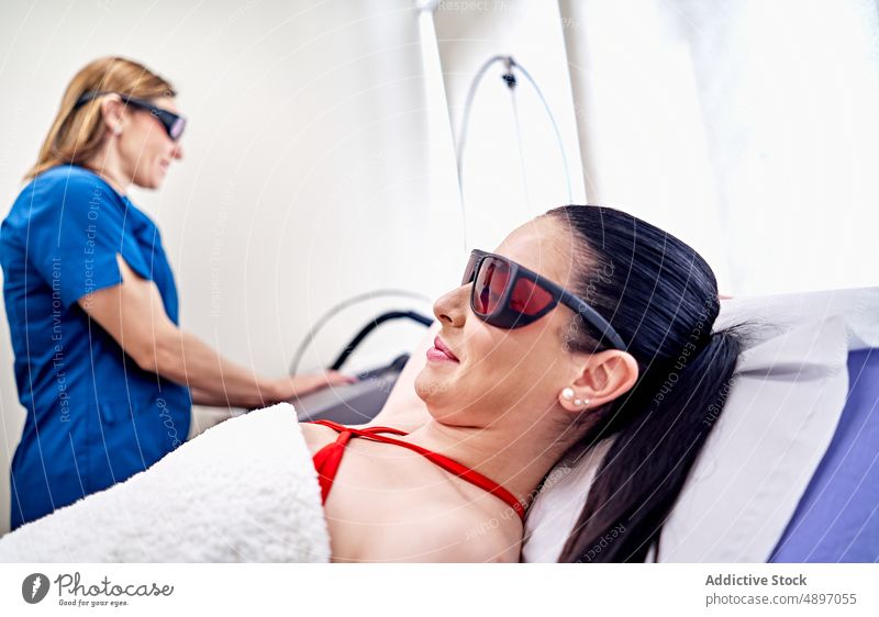 Woman in goggles waiting for laser epilation women client beautician prepare protect machine female equipment salon procedure aesthetic specialist job