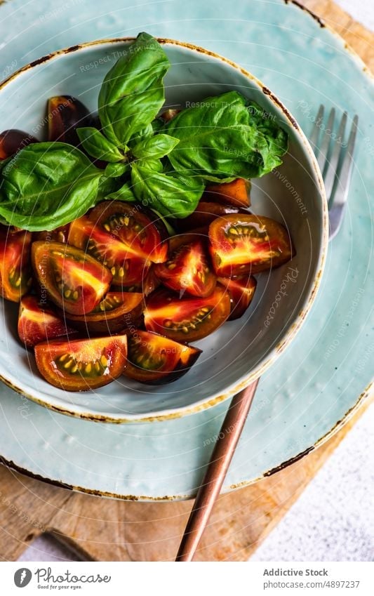 Raw organic tomato salad with basil herb bowl cherry tomato concrete table diet dinner eat eating food fresh healthy meal raw seasonal spice vegan vegetable