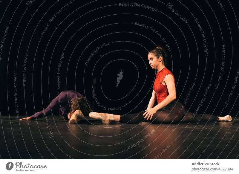 Ballet dancers stretching on stage ballet rehearsal split flexible theater together perform man woman grace choreography talent professional agile dark