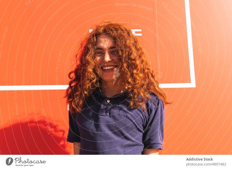 Happy Woman With curly hair Redhead Curly Hair Beautiful Sunlight Wall Lifestyle Arm Raised Leisure Tshirt Attractive Expression Front View Headshot Sunny