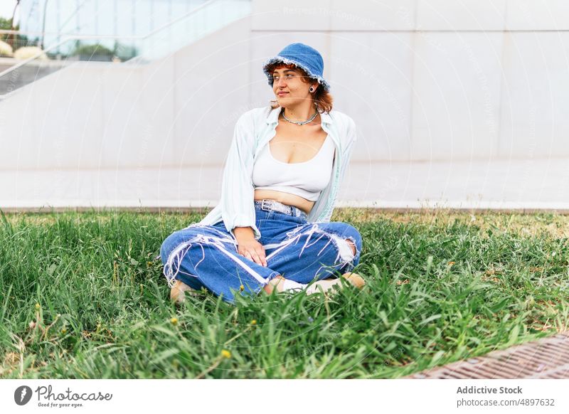 Woman sitting on lawn woman pastime leisure rest relax street grassy pleasant park feminine hat enjoy pleasure glade content activity casual attractive headwear