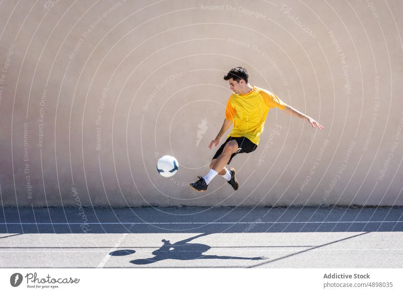 Young Male Player Kicking Football Soccer jump Building Court Motion Jumping Man Balance Determination City Ball Athlete Playing Sport Game Fitness Competition