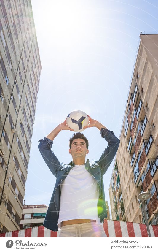 Low Angle View Of Man Playing With Football Young Sunny Sky City Building Motion Soccer Handsome Lifestyle Denim Jacket Serious Leisure Ball Standing Fashion