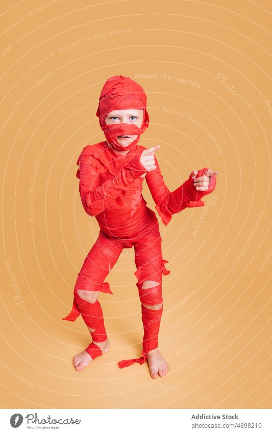 Funny child pretending being mummy during Halloween boy halloween make face funny costume event childhood play wrap barefoot kid arms raised holiday creative