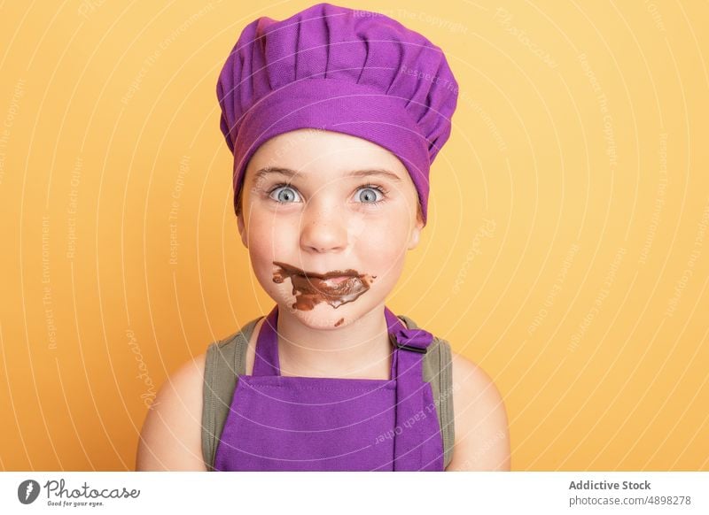 Funny girl covered with chocolate kid chef messy sweet cook helper culinary female mischievous treat mouth opened astonish amazed omg wow shock dirty childhood