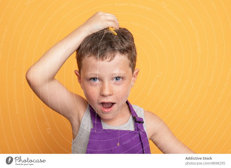 Cheerful boy breaking egg on head kid chef cook helper culinary having fun mischievous natural unruly product ingredient disobedient uncooked happy optimist