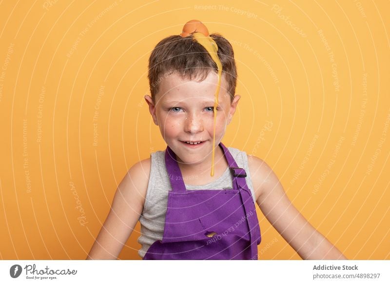 Mischievous boy with egg on head kid chef cook culinary having fun mischievous raw disobedient natural unruly helper product smile funny ingredient broken