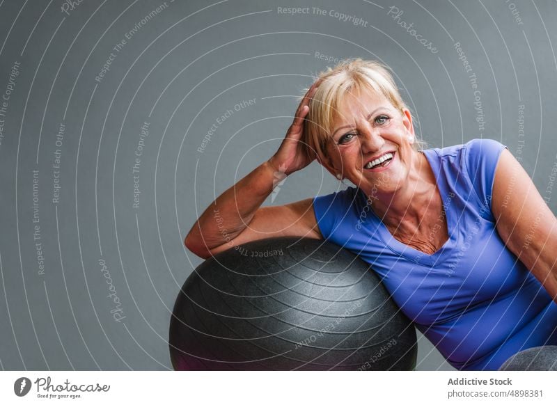 Smiling Fit Senior Woman Leaning On Fit Ball Elderly Looking Away Gym relax Pilates Exercise Workout Sporty Training Sitting Fitness Mat Happy Healthy Lifestyle