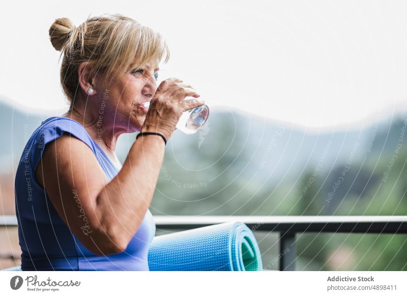 Cheerful Elderly Lady With Yoga Mat And Glass Of Water After Workout Senior Woman Holding Smile Looking Away Drink Refreshment Active Body Care Exercise Fit