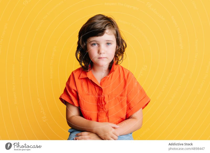 Calm girl in bright shirt calm casual colorful sit unhappy appearance portrait little style kid dark hair upset gray eyes vibrant sad serious brunette isolated