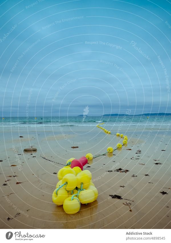 Yellow buoys on sandy beach near sea storm wave wet cloudy sky rope rias baixas spain galicia coast nature shore water weather ocean marine seaside summer roll