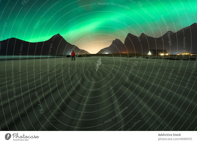 Anonymous traveler contemplating mountains under under starry sky and northern lights nature highland landscape astronomy polar lights man night water tourist