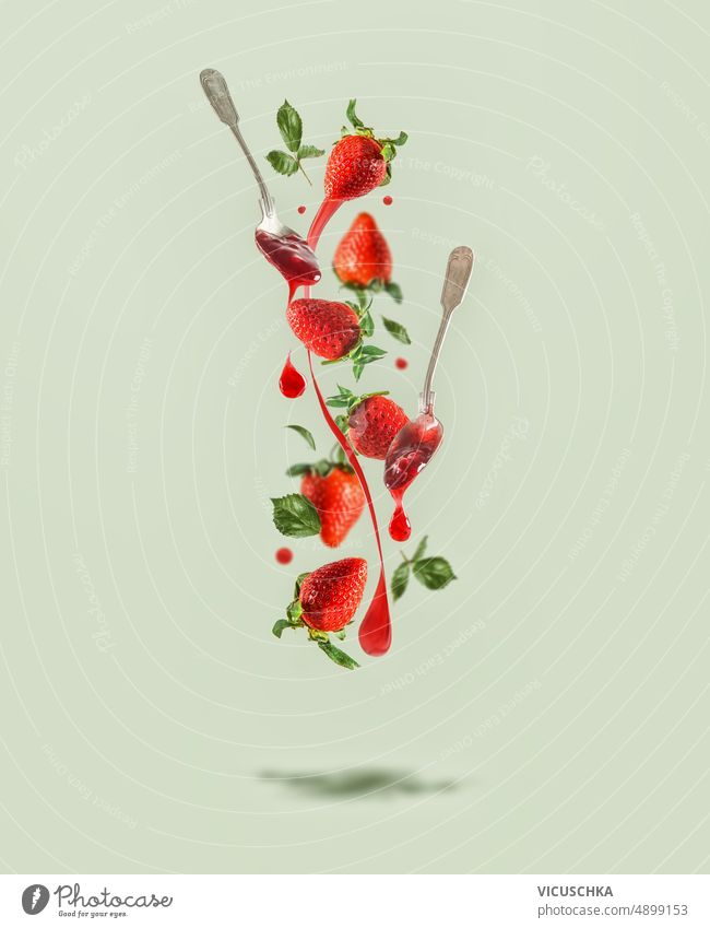 Flying strawberries with jam splash, spoons with dripping jam at pale green background with shadow. flying creative food levitation front view berry concept