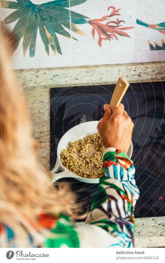 Unrecognizable woman frying quinoa on cooker stove kitchen culinary homemade dish cuisine meal spatula stir delicious prepare recipe female tasty appliance